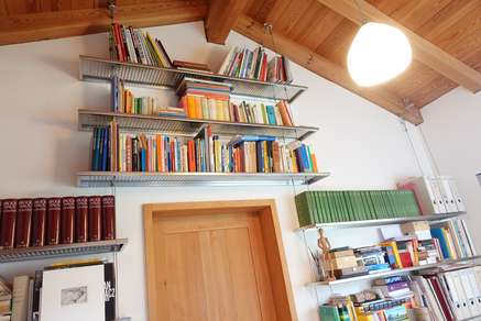 Bücherwand aus Edelstahlfachböden und Stahlseilen 